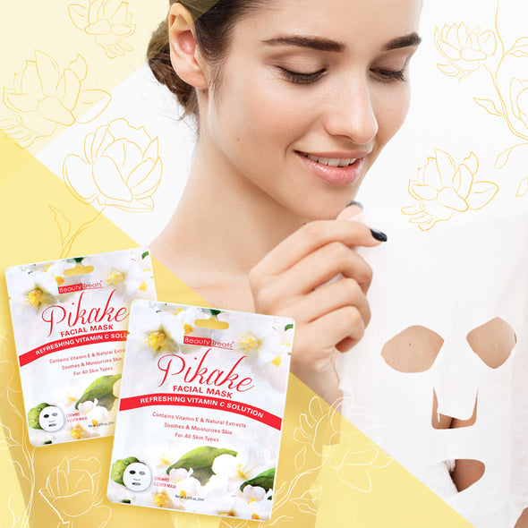 Two packs of Beauty Treats' facial mask in the scent of Pikake flower. In the background a woman holds up a sheet of facial mask.